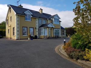 a yellow house with a black roof on a street at Sleepy Hollow B&B in Donegal