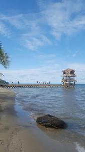 a pier in the ocean with a beach with a rock at Hotel Salvador Gaviota in Lívingston