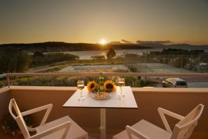 a table with glasses of wine and flowers on a balcony at Gliving365 Capital in Argostoli