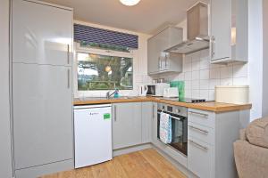 a kitchen with white cabinets and a white refrigerator at Mount Hawke Holiday Bungalows in Porthtowan