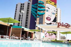 a pool with chairs and umbrellas in front of a building at Plaza Hotel & Casino in Las Vegas