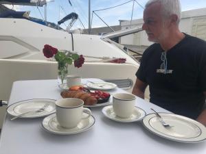 un hombre sentado en una mesa con tazas y platos de comida en Yacht Summertime 3 Bedrooms, en Menton