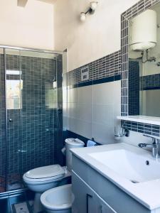 een badkamer met een wastafel, een toilet en een spiegel bij Casa Alice in Siracusa