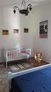 ソルソにあるCasa Marina Lu Tuvaraggiu Casa vacanzeのベビーベッド1台と椅子1脚が備わるベッドルーム1室が備わります。