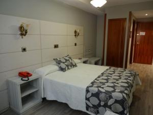 a bedroom with a bed with a black and white blanket at Hotel Los Naranjos in Cáceres