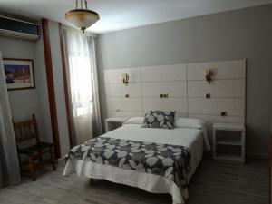 a bedroom with a bed and a chair and a window at Hotel Los Naranjos in Cáceres