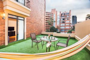 a hammock on a balcony with a table and chairs at Hotel Rosales Plaza in Bogotá