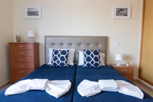 a bedroom with a blue bed with two white towels at Penthouse Cabanas Sun - Algarve in Cabanas de Tavira