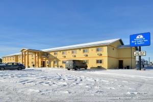 un edificio amarillo con una furgoneta estacionada en un estacionamiento en Americas Best Value Inn and Suites Sidney, en Sidney