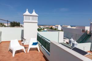 uma varanda com duas cadeiras brancas e um farol em Penthouse Cabanas Sun - Algarve em Cabanas de Tavira