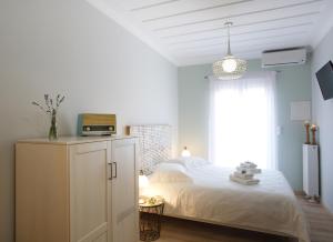 ein weißes Schlafzimmer mit einem Bett und einem Fenster in der Unterkunft Casa di fiori in Lefkada Town