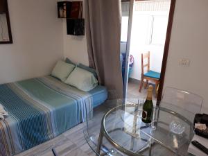 ラス・ガジェタスにあるLovely studia in Las Galletas con nice sea viewのベッド、ガラステーブル、ワイン1本が備わる客室です。