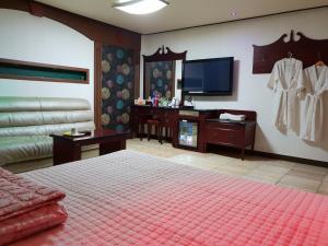 a bedroom with a bed and a flat screen tv at Plus Motel in Busan