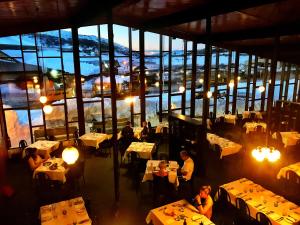 a restaurant with people sitting at tables in a room with windows at The Man from Snowy River Hotel in Perisher Valley
