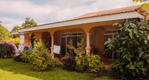 a small yellow house with plants in the yard at Fare Om in Pihaena