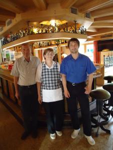 three people standing in front of a bar at Hotel Pensione Dolomiti in Falcade