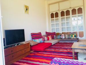 sala de estar con sofá rojo y TV de pantalla plana en CosyFlat 10minBeach en Agadir