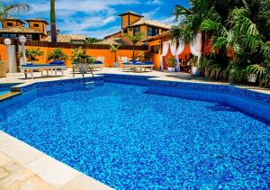 uma piscina com água azul em frente a uma casa em Villa Baobá em Búzios