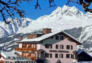 a hotel with snow covered mountains in the background at Hotel Central in Obersaxen