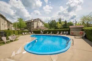 a swimming pool in a yard with chairs and a building at Condo de L'Oberge in Magog-Orford