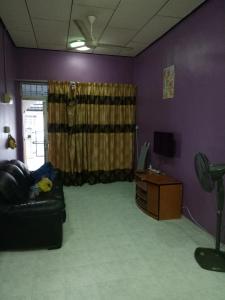 ドゥングンにあるSyahril homestayの紫の壁のリビングルーム(ソファ、テレビ付)