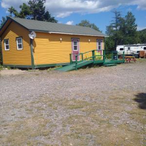 ein gelbes Haus mit einer Veranda und einem Hof in der Unterkunft Princehaven Campground in Princeton