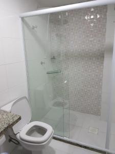 y baño con ducha de cristal y aseo. en Apartamento de 3 Quartos Praia Grande, en Arraial do Cabo