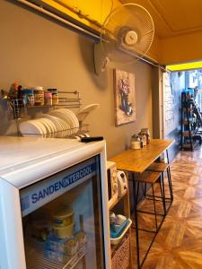 a kitchen with a refrigerator and a table with a fan at U2 & i-smile Hostel in Chiang Mai