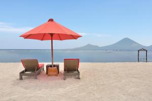 two chairs and an umbrella on the beach at Ombak Sunset in Gili Trawangan