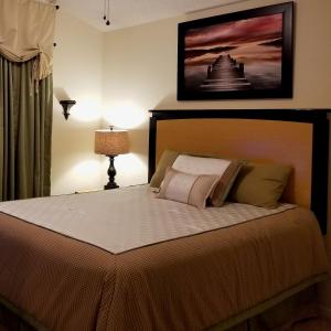 a bedroom with a bed with a picture on the wall at Key 2 Indian Creek Pool Home in Kissimmee