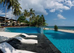 a swimming pool with white chairs and the beach at Katamaran Hotel & Resort in Senggigi 