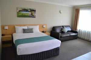 a hotel room with a bed and a chair at Bathurst Motor Inn in Bathurst