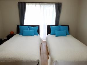 two beds with blue pillows in a room with a window at Episode1 in Naoshima