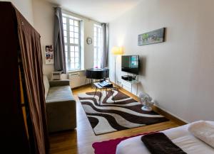 ein kleines Wohnzimmer mit einem Sofa und einem TV in der Unterkunft Noella's Suite in Lille