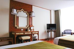 a hotel room with a mirror and a desk at Chiang Mai Orchid Hotel SHA EXTRA PLUS in Chiang Mai