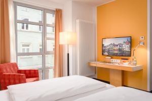 a hotel room with a bed and a desk with a television at Hotel Nepomuk in Bamberg