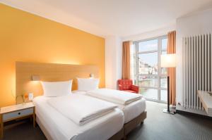 バンベルクにあるホテル ネポムクのベッド2台と窓が備わるホテルルームです。