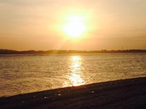 una puesta de sol sobre un cuerpo de agua con una playa en Blu d'aMare, en Gili Trawangan