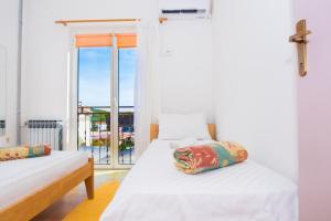 a bedroom with two beds and a large window at Apartmani Šutić in Promajna