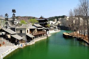 een rivier met een groep gebouwen naast een stad bij Jumanyuan House in Miyun