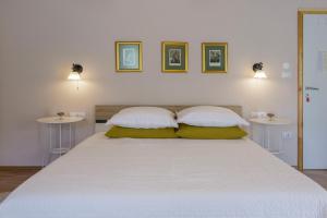 a bedroom with a large white bed with two tables at Apartments Mardešić in Komiža