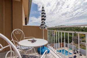 a balcony with a table and chairs and an umbrella at Apartments Mardešić in Komiža