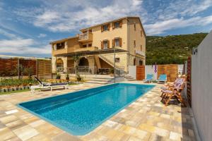 a villa with a swimming pool in front of a house at Apartments Mardešić in Komiža