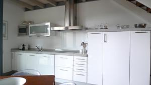 cocina con armarios blancos y microondas en Las Villas de Cué en Llanes