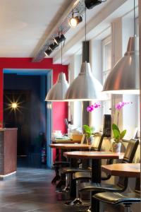 ein Restaurant mit Tischen, Stühlen und Hängelampen in der Unterkunft BXLROOM Guesthouse in Brüssel