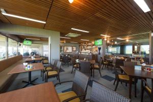 un restaurante con mesas y sillas y un bar en The Southern Links Resort Hotel, en Yaese