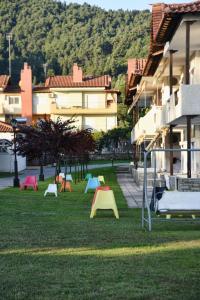 a group of colorful tables in the grass next to buildings at Haus Platanos Apartments & Bungalows by the Sea in Vourvourou
