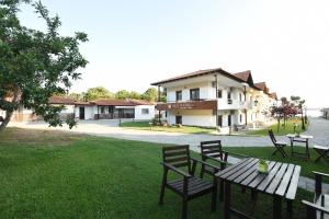 a picnic table and chairs in front of a house at Haus Platanos Apartments & Bungalows by the Sea in Vourvourou