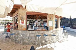 a woman sitting at a bar with stools at Haus Platanos Apartments & Bungalows by the Sea in Vourvourou