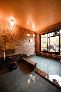 a bathroom with a tub with a sink and a mirror at Ryokan Tamura in Kusatsu